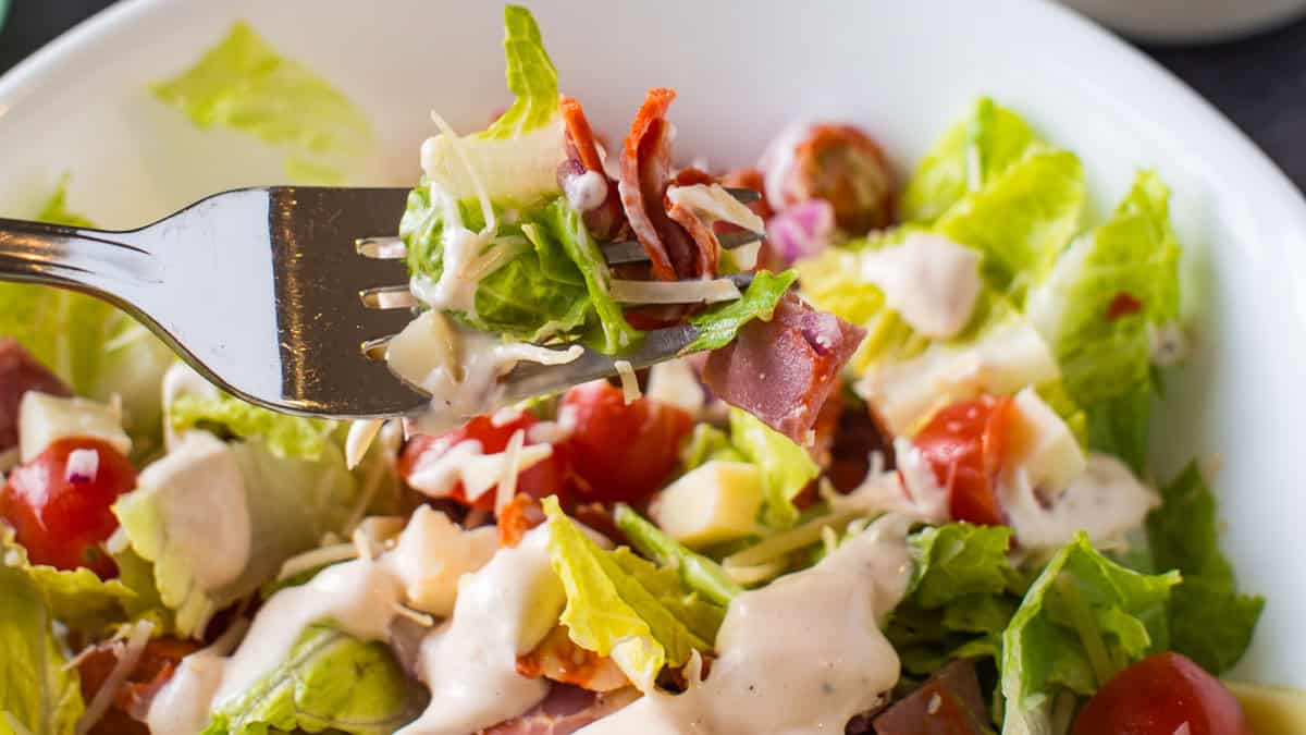 Salad with lettuce, cherry tomatoes, salami, and cheese.