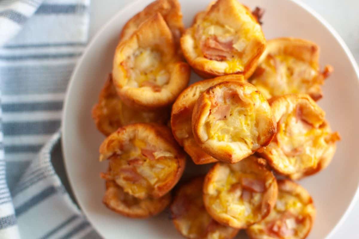 Overhead close-up of a white plate filled with small, golden-brown Ham & Cheese Puffs.