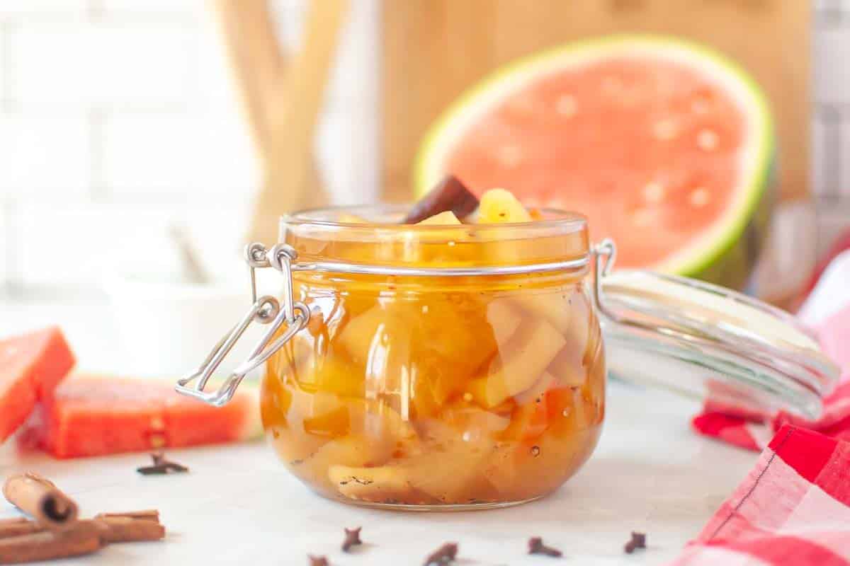 A glass jar filled with preserved watermelon rinds and cinnamon sticks are visible in the background.