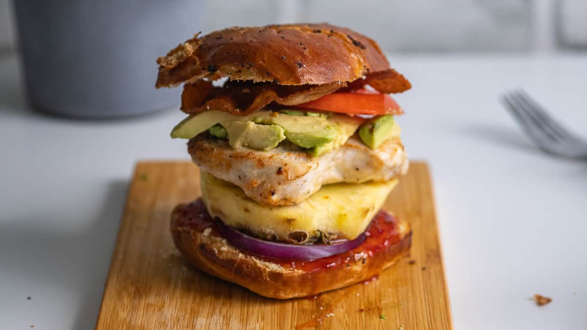 Chicken sandwich with pineapple on a cutting board.