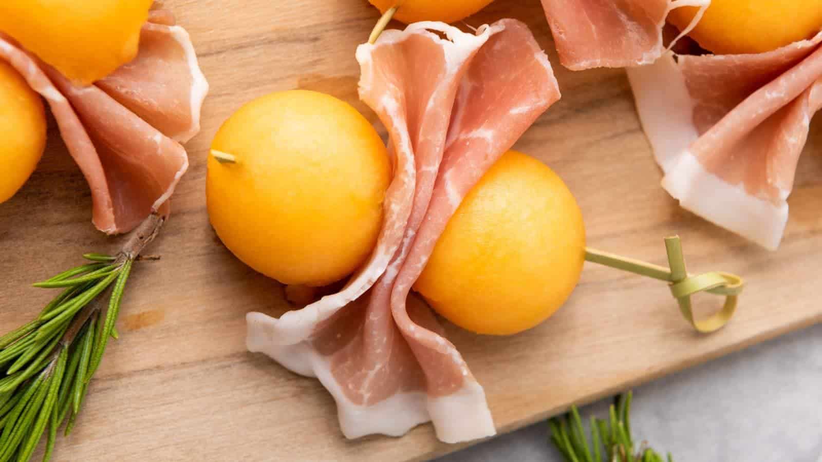 Slices of prosciutto e melone wrapped around cantaloupe balls, skewered.