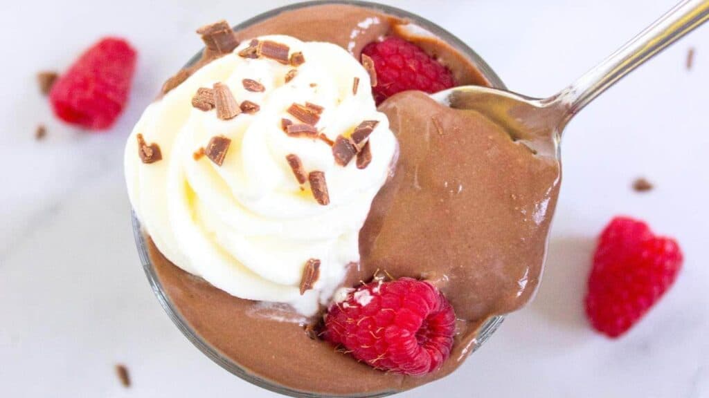A glass cup filled with protein pudding topped with whipped cream.