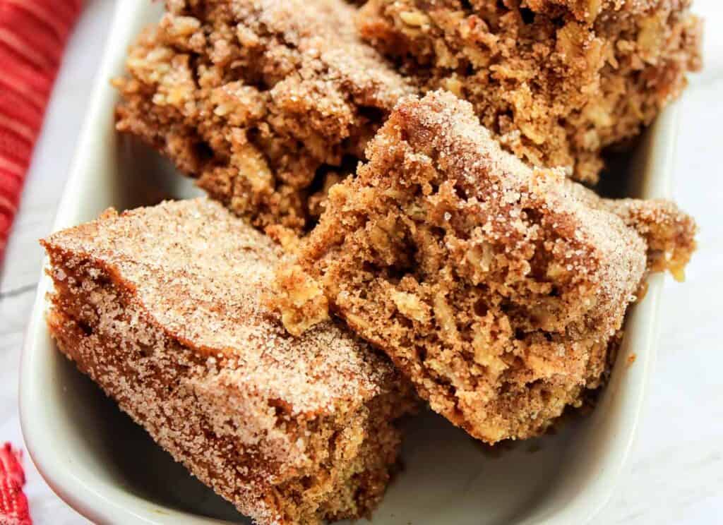 Close-up of several cinnamon sugar-coated oat bars arranged in a white dish.