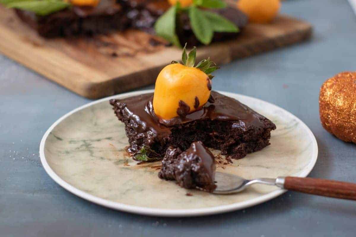 A slice of Chocolate Pumpkin Patch Brownie Cake sits on a plate, accompanied by a fork.