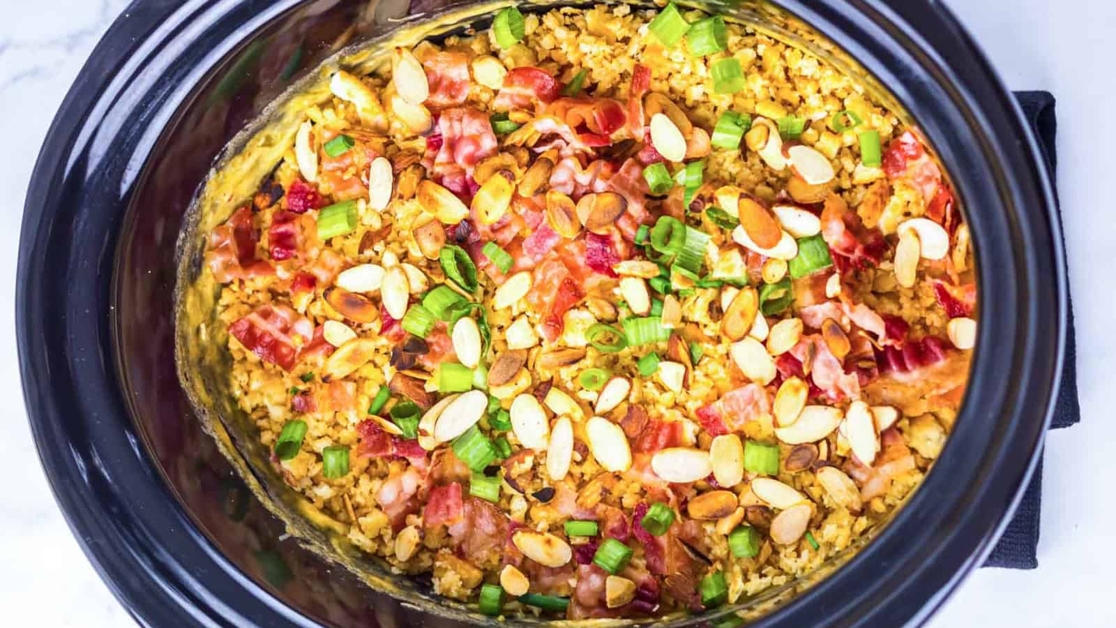 Plate of creamy chicken casserole topped with sliced almonds and green onions, served with crackers.