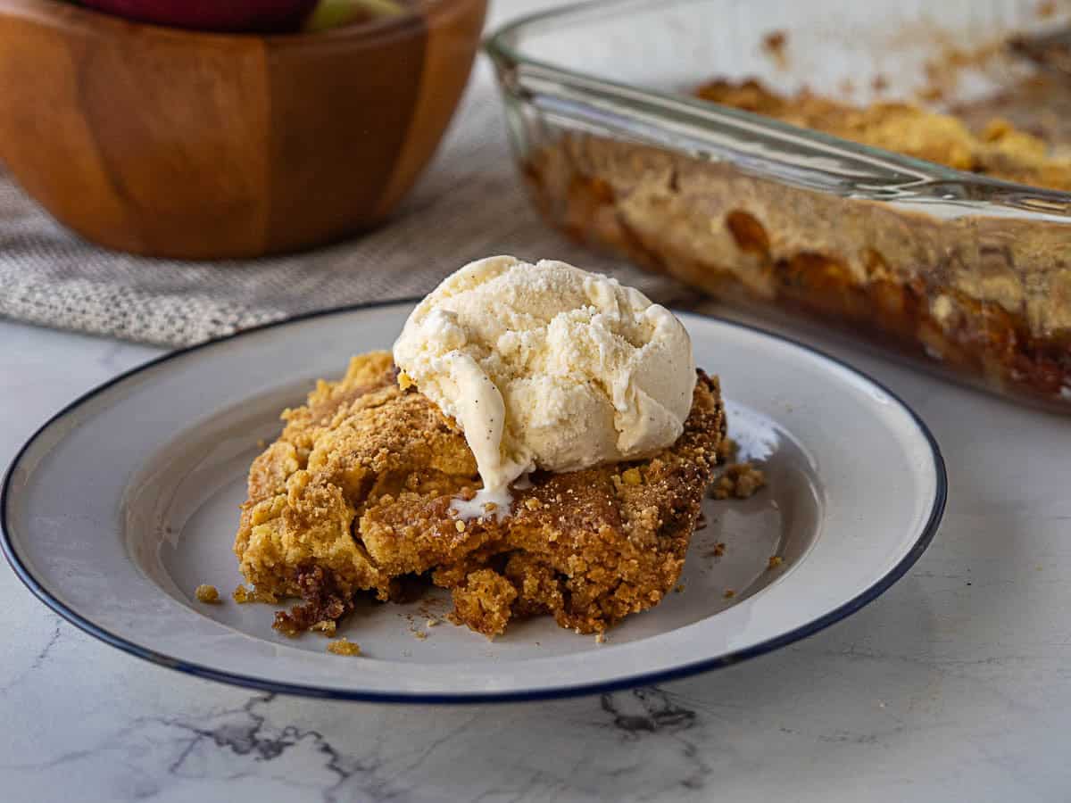Apple dump cake on a plate with ice cream.