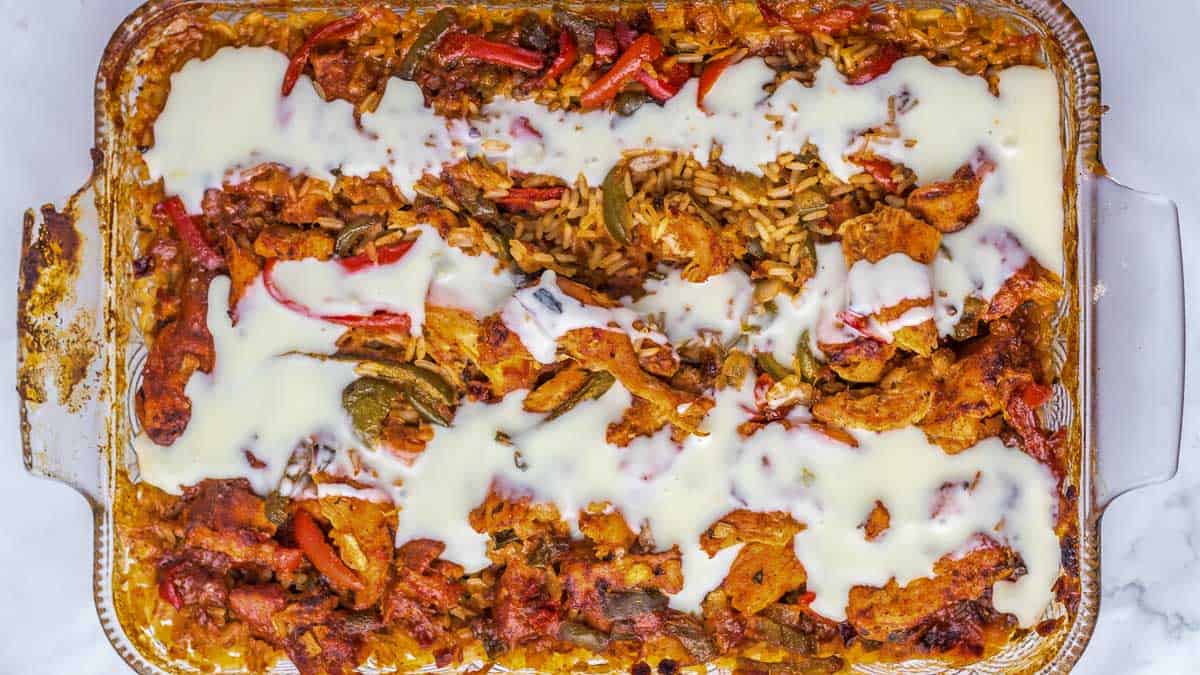 A casserole dish filled with baked vegetables, rice, and melted cheese topping.