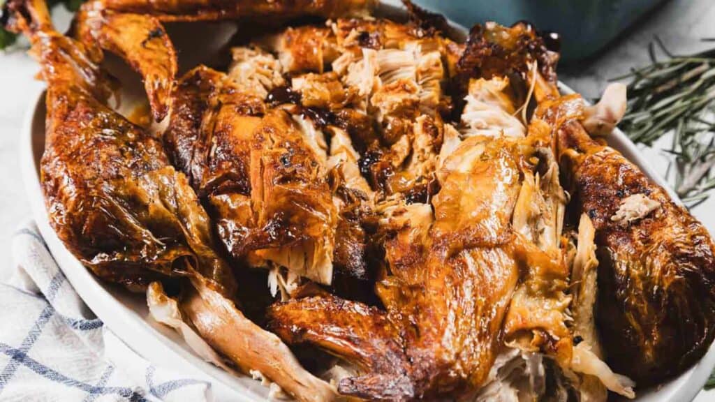Platter of roasted turkey meat, carved into large pieces and arranged on a white dish.