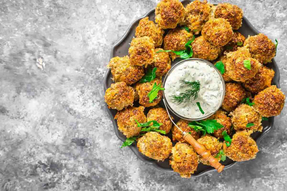 Sausage balls garnished with parsley around sauce.