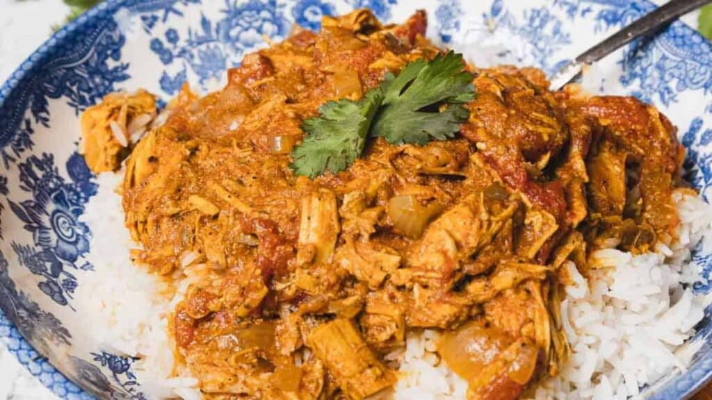 Shredded chicken in a tomato-based sauce served over white rice, garnished with fresh cilantro.