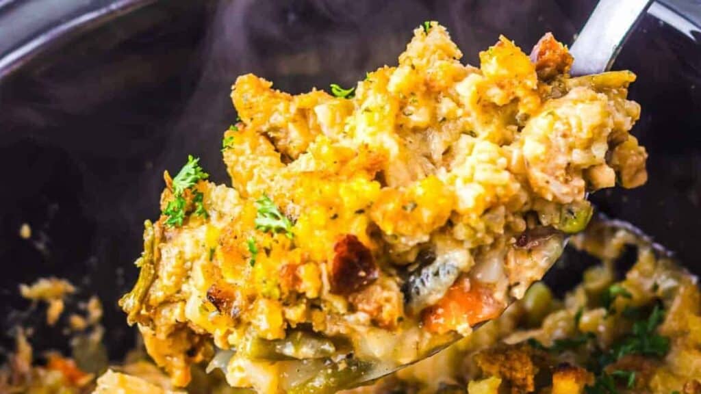 A spoonful of creamy chicken and stuffing casserole garnished with herbs.