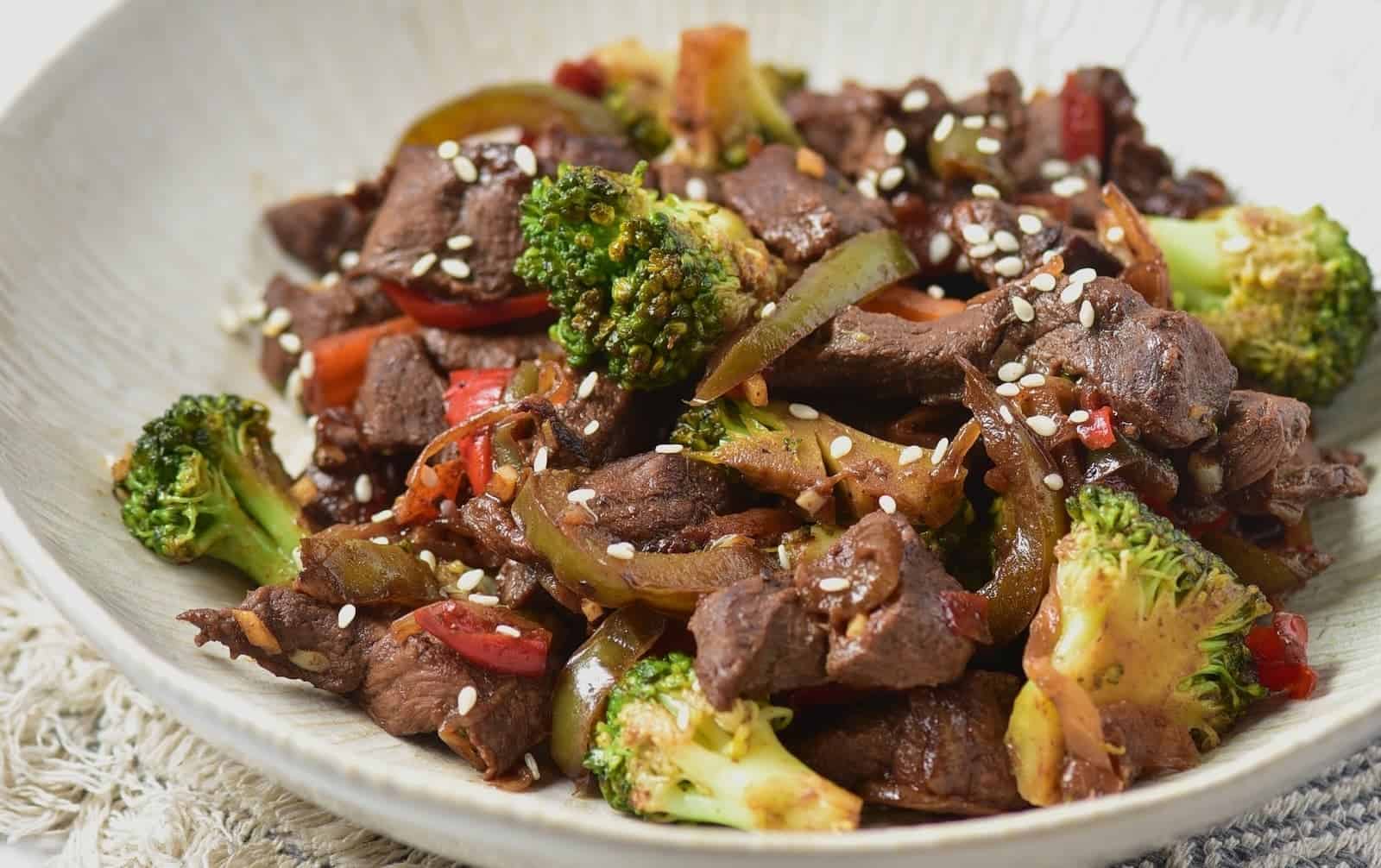 Venison stir fry served on a white textured plate.