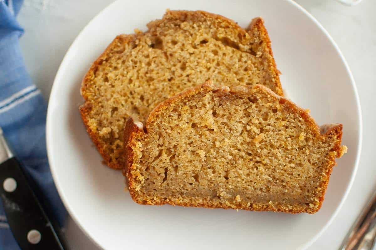Two slices of Butternut Squash Loaf with Spiced Icing are placed on a white plate, showing a moist and dense texture with a golden-brown crust.