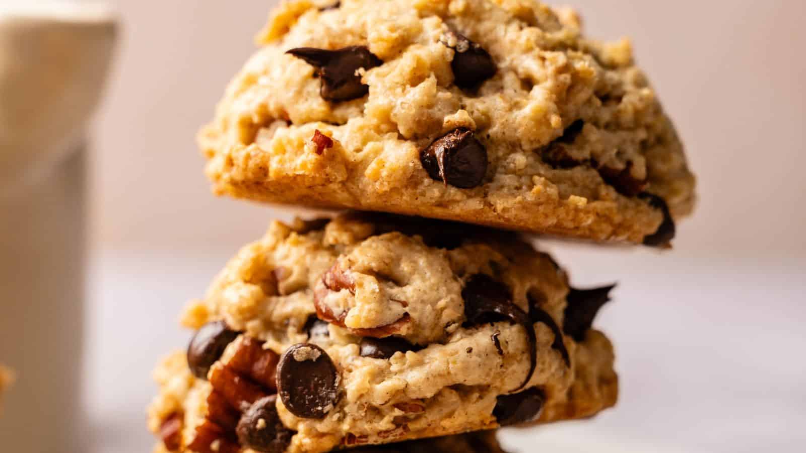 Two chocolate chip cookies with nuts stacked on top of each other in close-up view.