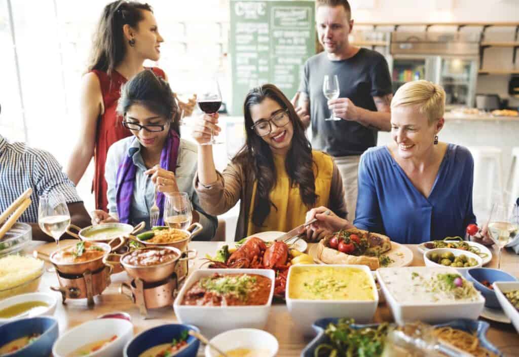 A group of people sitting at a table with various dishes, raising glasses, and smiling in a restaurant setting.