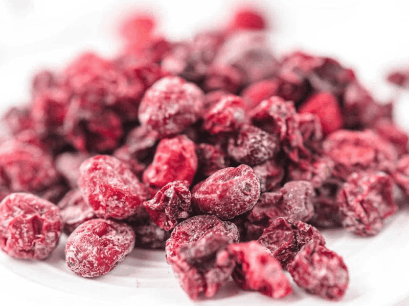 A close-up view of a pile of dried cranberries on a white surface.