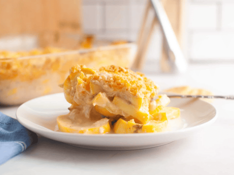 A serving of squash casserole with a crumb topping is plated on a white dish.
