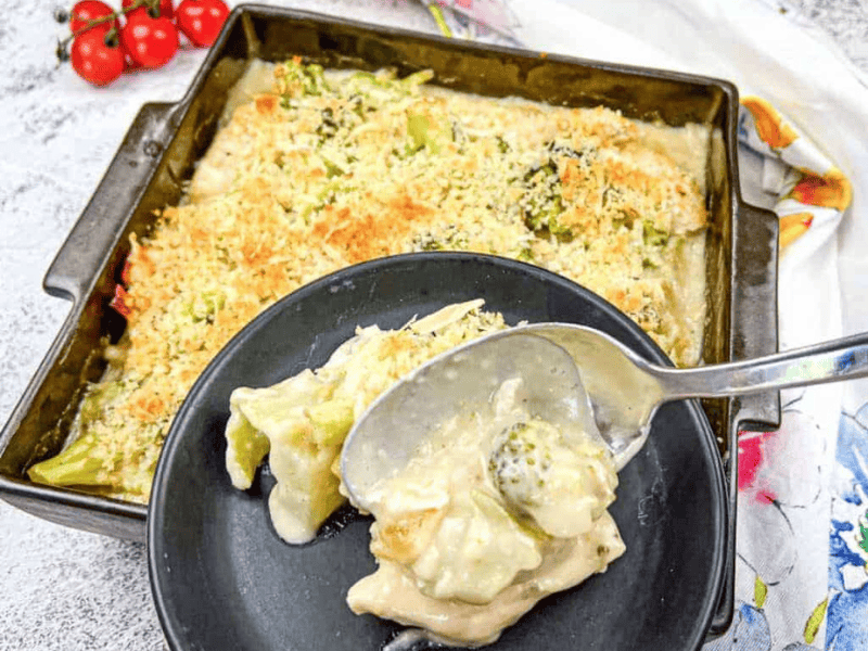 A serving of Turkey Divan from a baking dish onto a black plate.