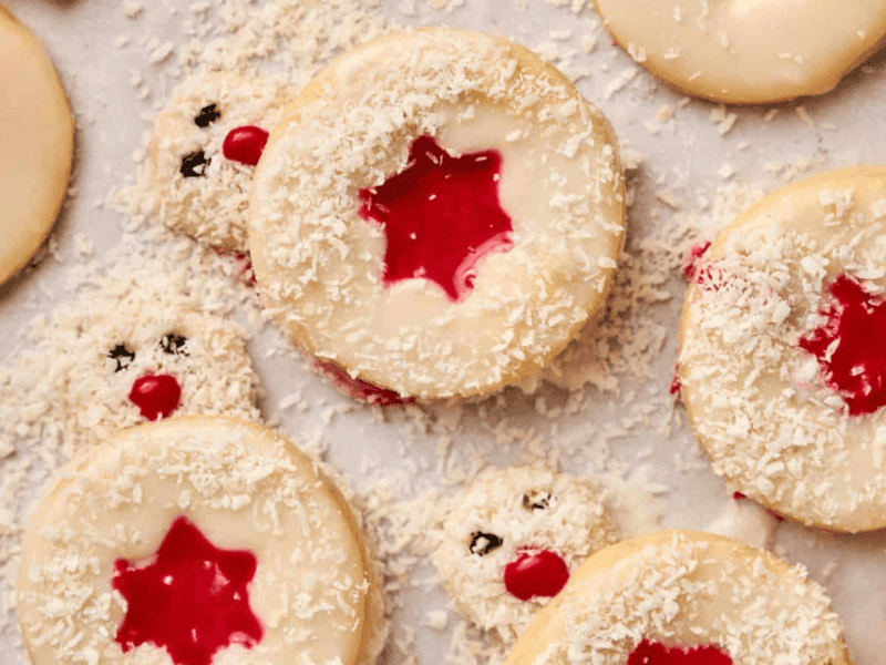 Christmas cookies with cherries and icing on a baking sheet.