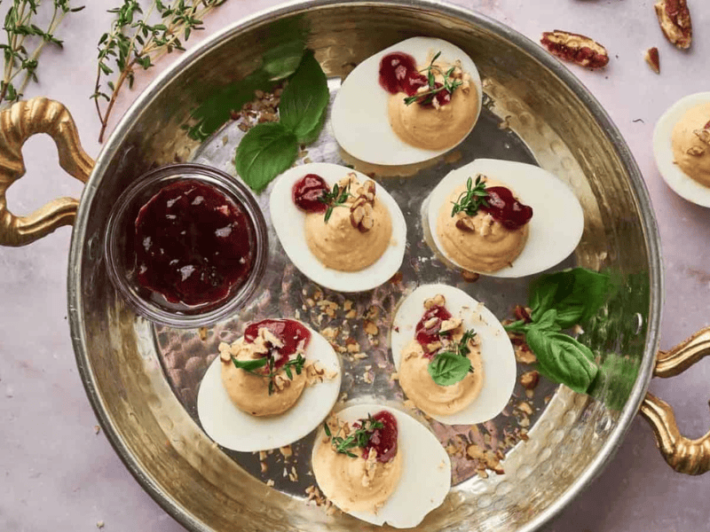 Deviled eggs with cranberry sauce on a platter.