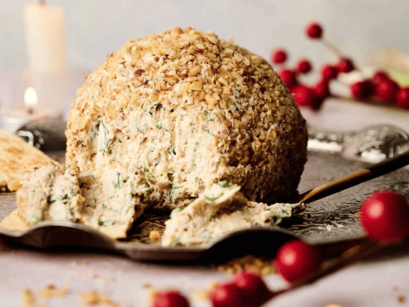 A cheese ball on a cutting board with crackers.