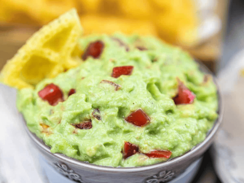 Guacamole Dip with Sour Cream in a bowl with chips.