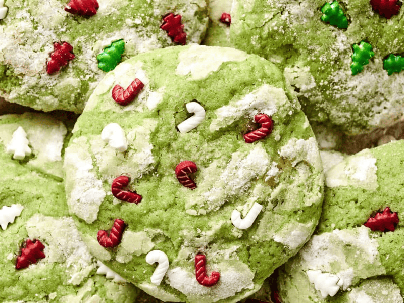 Green cookies topped with red and white candy cane sprinkles and white and green Christmas tree sprinkles, dusted with powdered sugar.