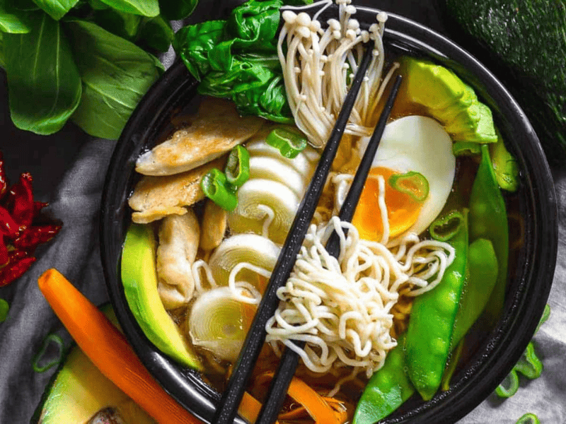 Keto Ramen Chicken Noodles in a black bowl with various vegetables and boiled egg.