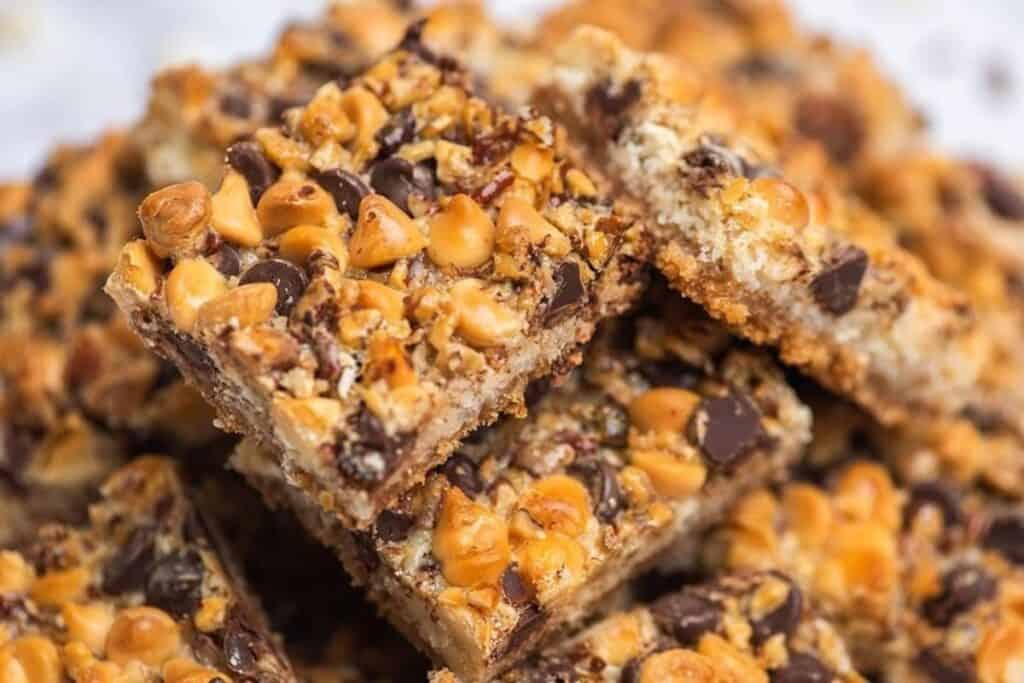 Close-up view of stacked dessert bars topped with chocolate chips, butterscotch chips, and chopped nuts.
