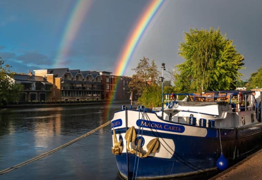 A rainbow arches gracefully over a luxury barge cruise, creating a magical moment on the water.
