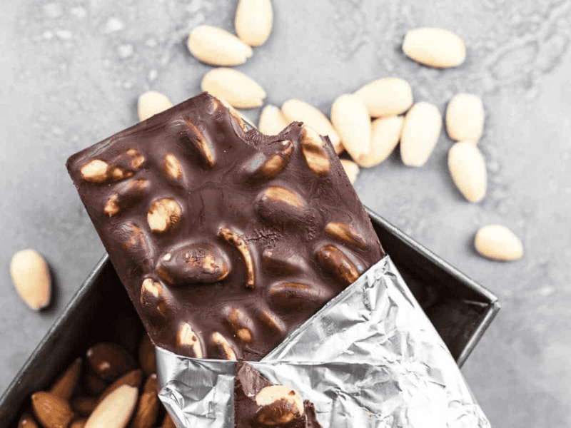 Chocolate bar with almonds partially unwrapped.