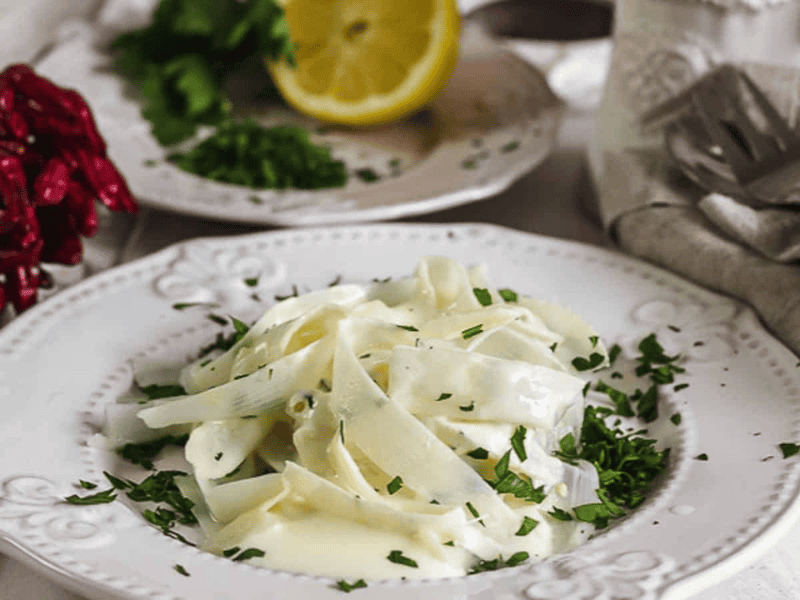 A white plate filled with asparagus pasta and sauce.