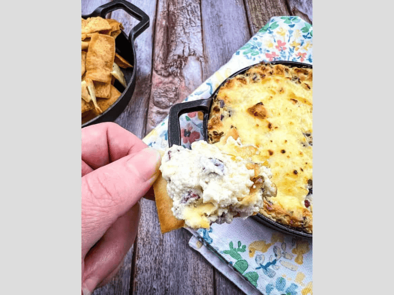 Beef jerky dip on a cracker held in a hand.