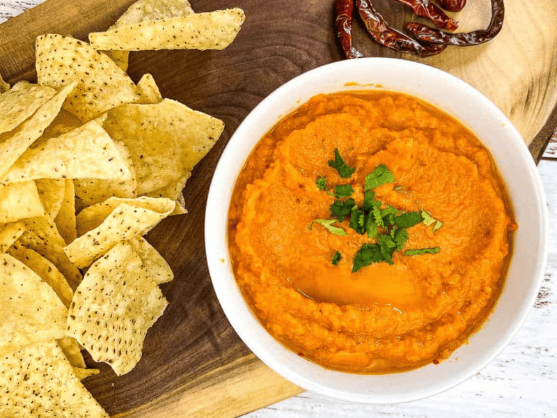 Chile de Arbol Salsa on wooden board with chips and chilies nearby.