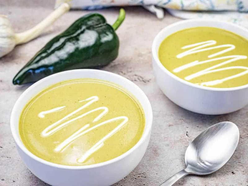 Two bowls of Cream of Poblano soup garnished with sour cream.