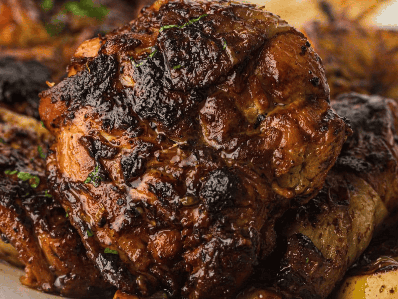 Close-up of grilled, well-seasoned, and charred chicken pieces with visible herbs on a plate.
