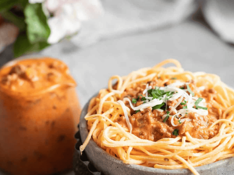 Low Carb Spaghetti Bolognese in a grey bowl with extra sauce on the side.