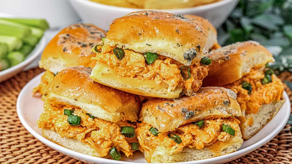 A close-up of a white dish filled with glazed meatballs garnished with chopped herbs.