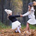 Two girls holding hands in the woods.