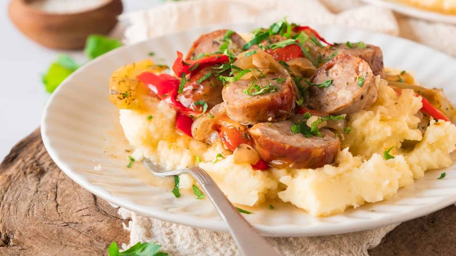Ready-to-serve oven-roasted sausage on a white plate with a fork resting on it.
