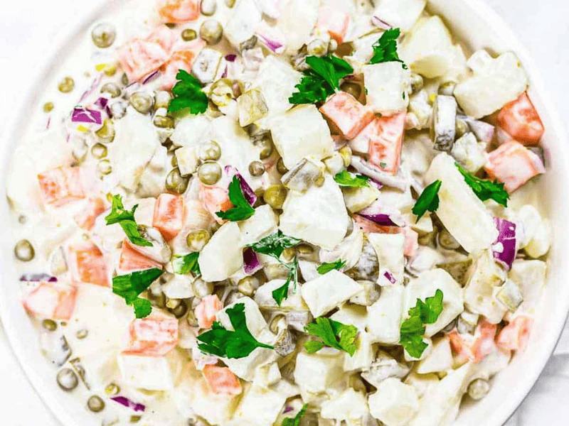 A white bowl of potato salad with mayonnaise.
