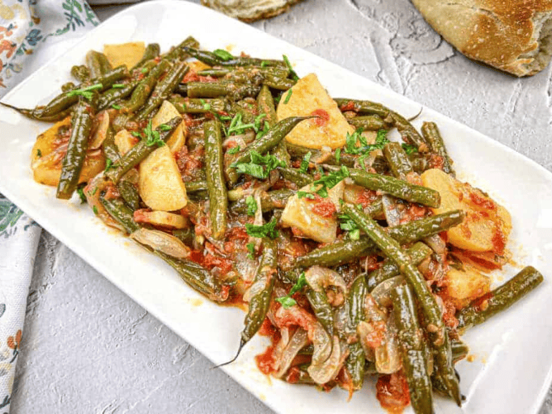 Greek Green Beans served on a white rectangular plate.
