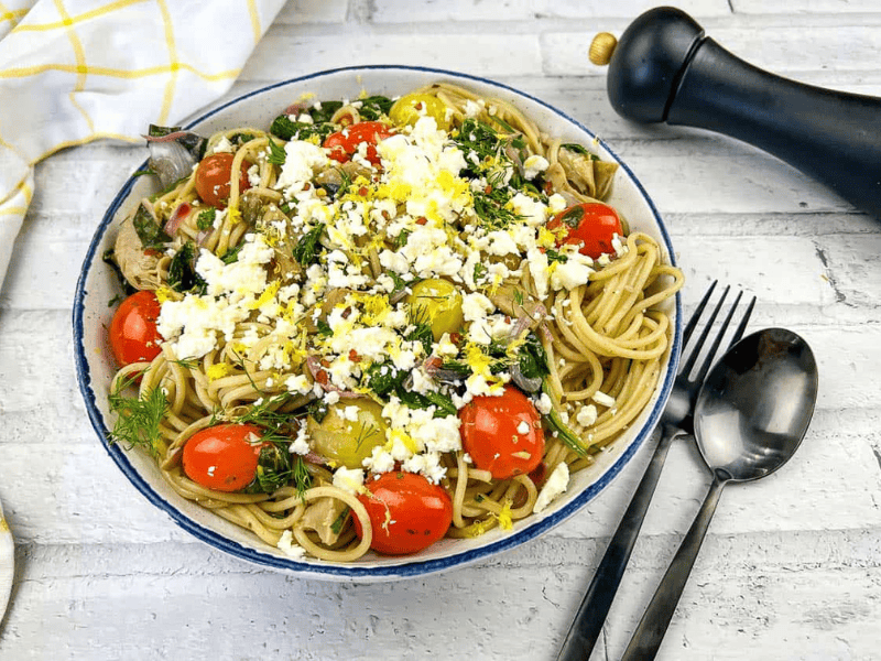A bowl of pasta with tomatoes, feta and kalamata olives.
