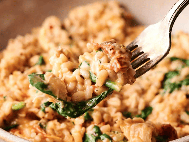 A slice of chocolate cream pie with a graham cracker crust, topped with whipped cream and chocolate shavings, served on a black plate.