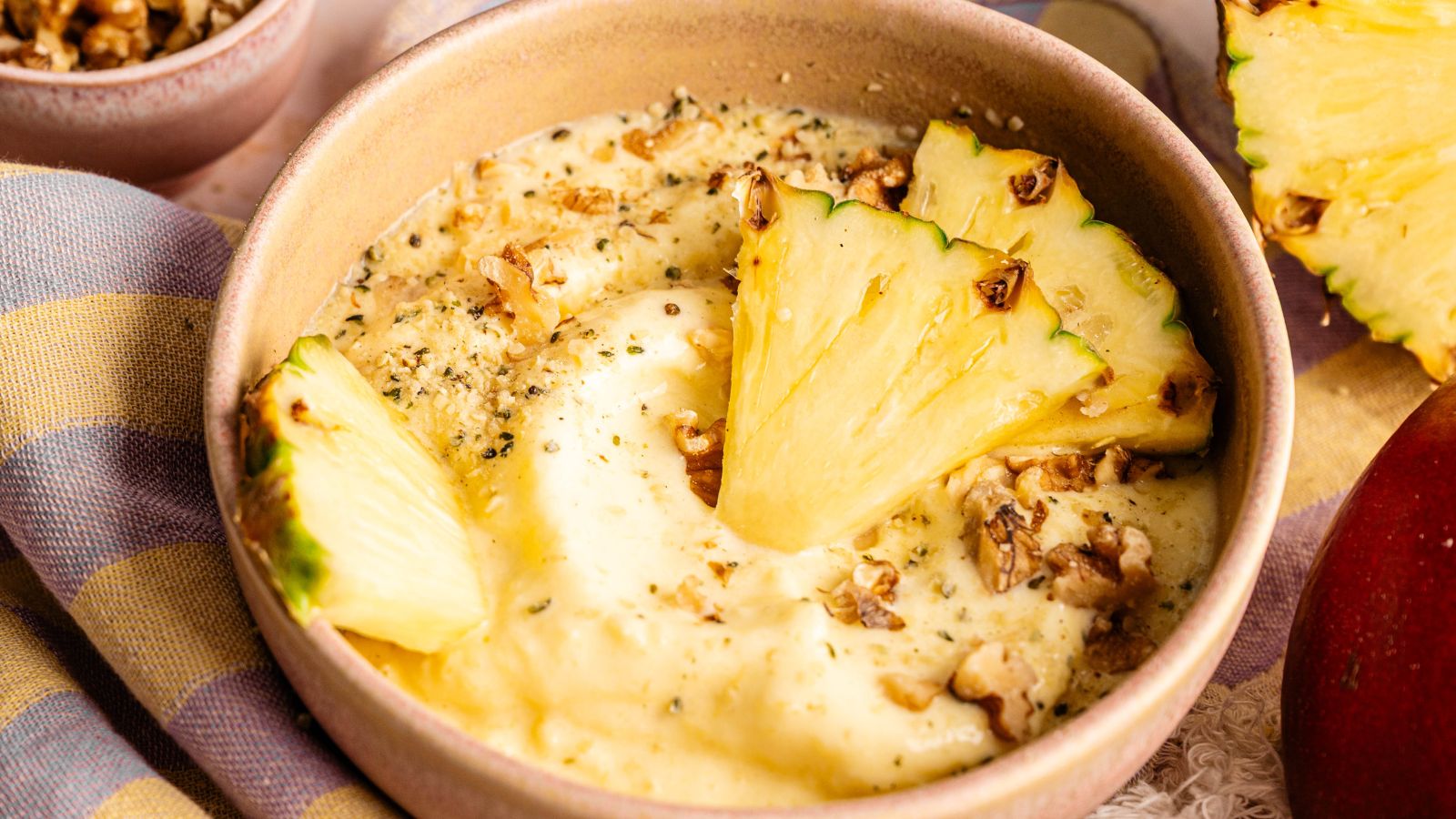 A bowl of vanilla ice cream topped with chopped nuts and drizzled with honey, with jars of honey and nuts in the background.