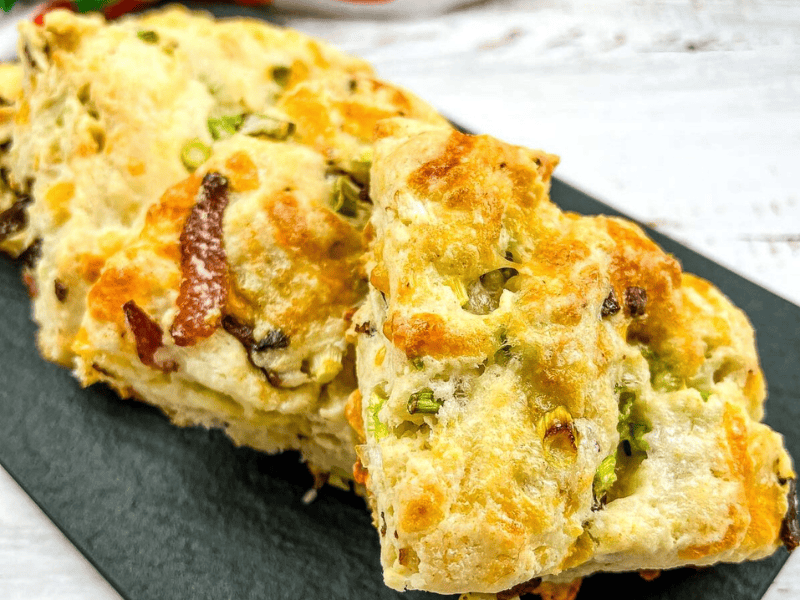 Bacon, Cheddar, Green Onion Scones on a black plate.