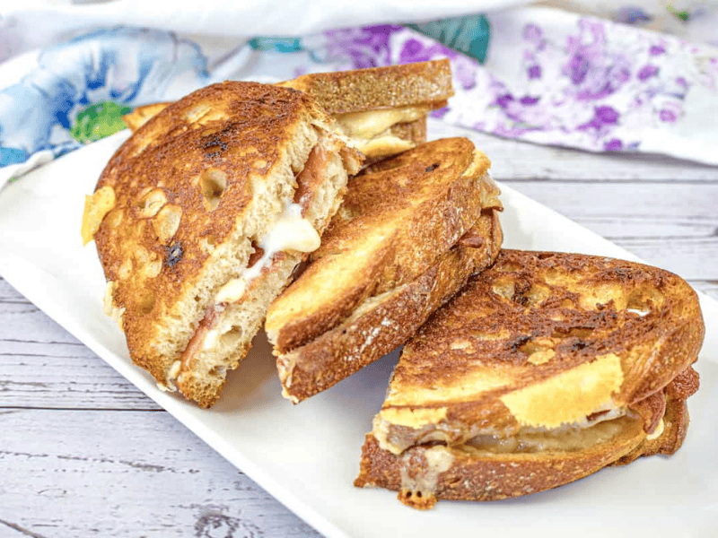 A plate with halves of Bacon Grilled Cheese Sandwiches with Hot Honey Butter.
