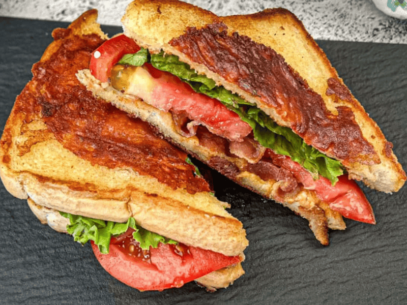 Two halves of Texas BLT on a black plate.