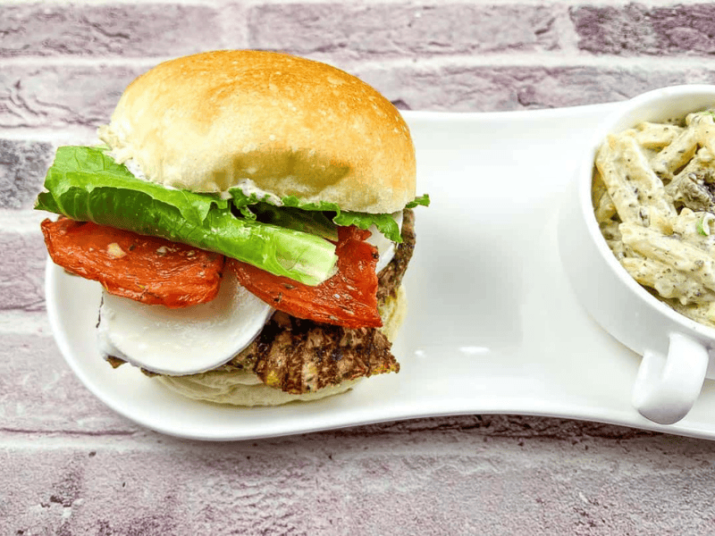 Grilled Chicken Caprese Sandwich served with a creamy pasta salad on side.