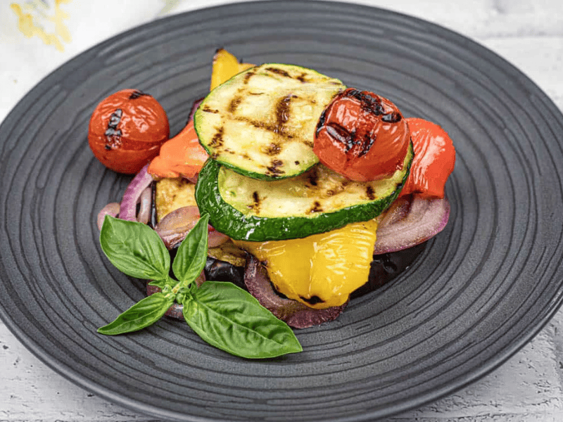 Close-up shot of Grilled Ratatouille on a black plate.